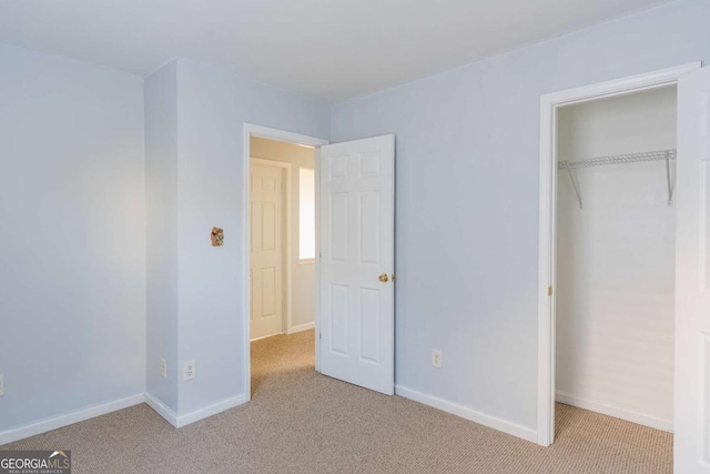 unfurnished bedroom featuring light carpet, a closet, and baseboards