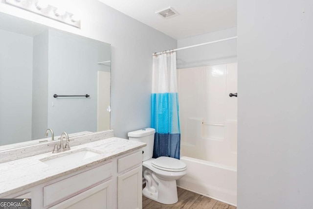 full bathroom with visible vents, toilet, wood finished floors, vanity, and shower / bathtub combination with curtain