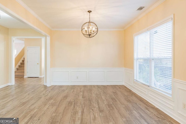 empty room with visible vents, light wood-style floors, a chandelier, and crown molding