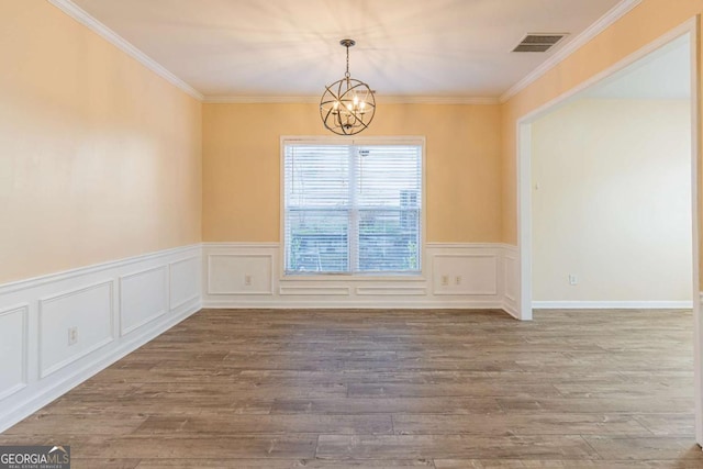 spare room with visible vents, a notable chandelier, wood finished floors, and ornamental molding