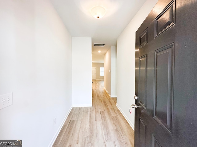 corridor with light wood-style floors, visible vents, and baseboards