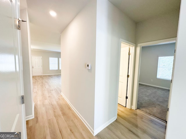 hall with baseboards and light wood-style floors