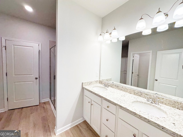 full bathroom with a sink, baseboards, wood finished floors, and double vanity