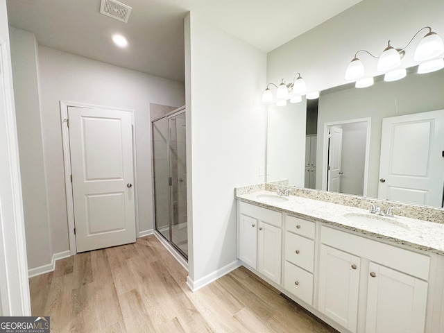 full bathroom with a shower stall, wood finished floors, visible vents, and a sink