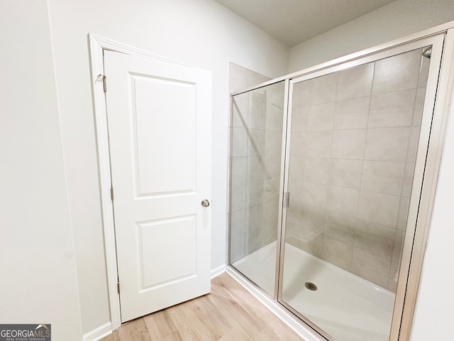 bathroom with a shower stall and wood finished floors