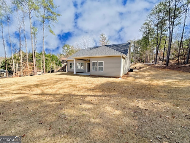 rear view of house with a ceiling fan and a lawn