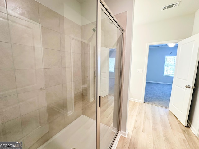 bathroom with visible vents, a shower stall, baseboards, and wood finished floors