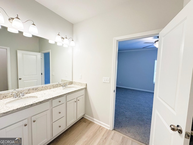 full bath featuring double vanity, wood finished floors, baseboards, and a sink