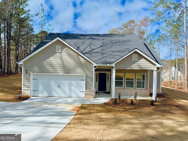 view of front of house with driveway, roof with shingles, covered porch, a garage, and brick siding