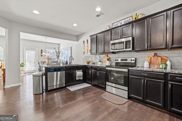 kitchen with tasteful backsplash, visible vents, light stone countertops, stainless steel appliances, and a sink