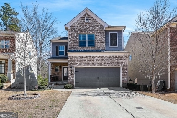 traditional home with concrete driveway, an attached garage, and brick siding