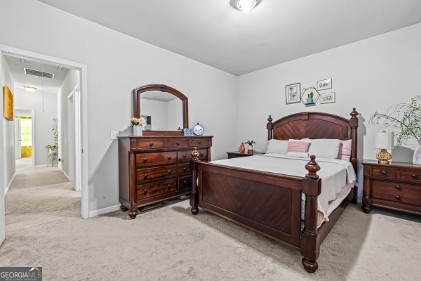 bedroom with attic access, light colored carpet, visible vents, and baseboards