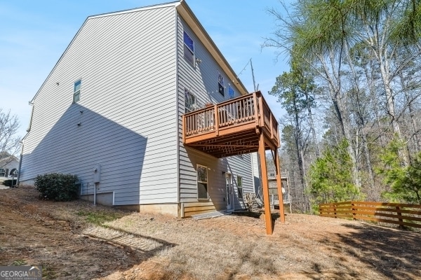 back of property featuring a deck and fence