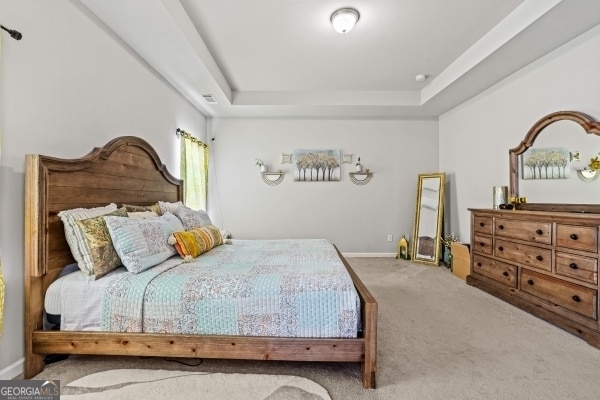 bedroom featuring baseboards, visible vents, a raised ceiling, and carpet floors