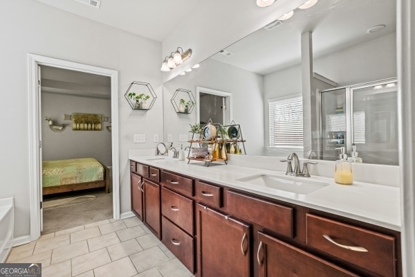 bathroom with double vanity, tile patterned flooring, a shower with door, and a sink