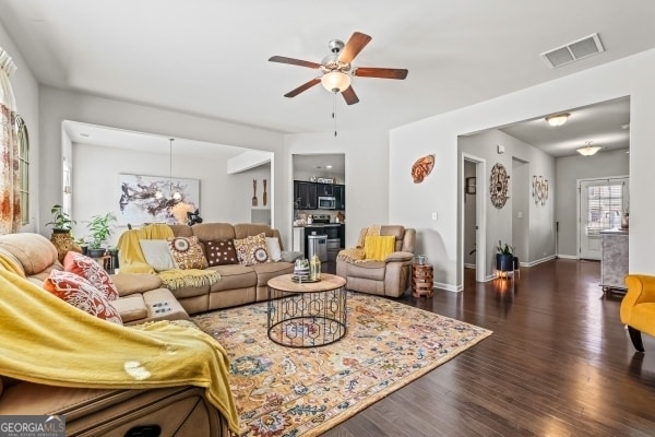 living room with visible vents, baseboards, a ceiling fan, and dark wood-style flooring