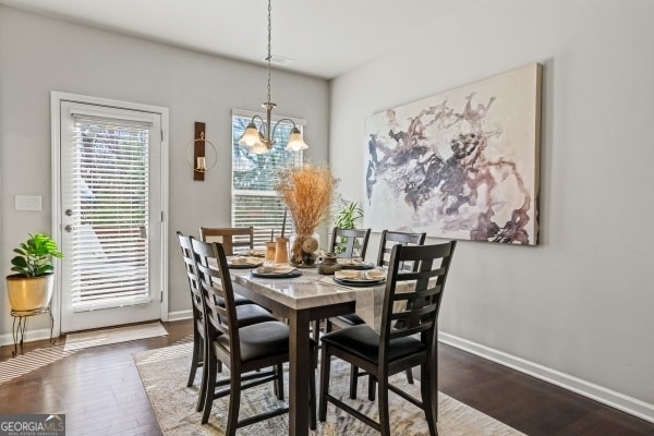 dining area with an inviting chandelier, dark wood-type flooring, and baseboards