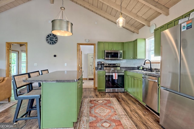 kitchen with green cabinetry, a sink, appliances with stainless steel finishes, dark countertops, and backsplash