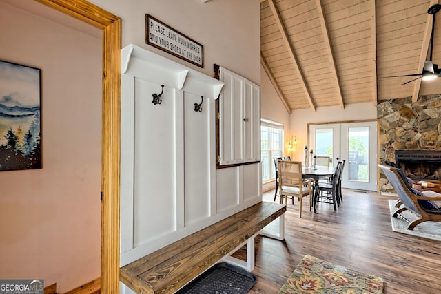 interior space featuring beam ceiling, a stone fireplace, wooden ceiling, and wood finished floors