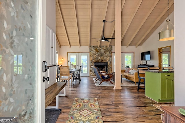 foyer entrance featuring beamed ceiling, plenty of natural light, a stone fireplace, and dark wood-style flooring