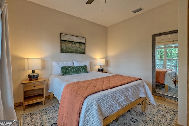 bedroom with tile patterned floors, visible vents, and ceiling fan