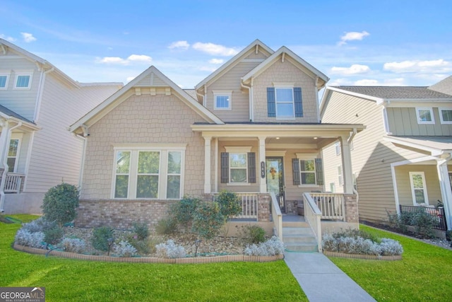 craftsman house with brick siding, a porch, and a front yard