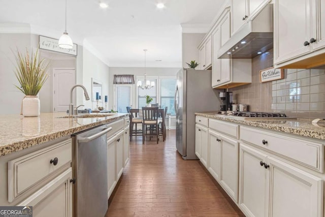 kitchen with backsplash, crown molding, under cabinet range hood, wood finished floors, and stainless steel appliances