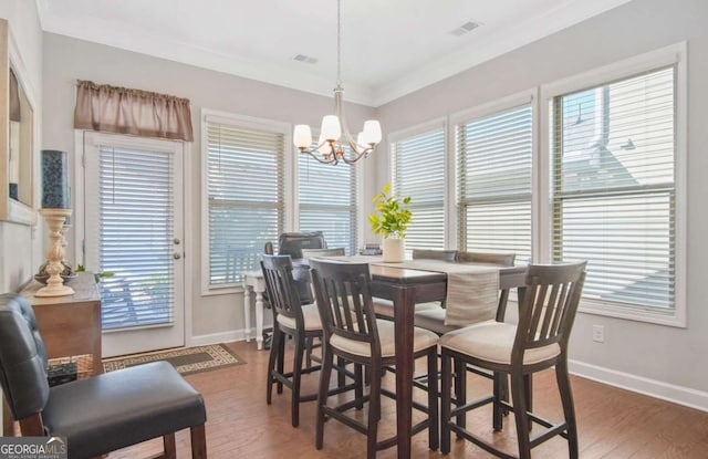 dining space with a notable chandelier, crown molding, baseboards, and wood finished floors