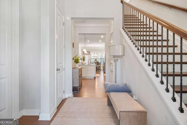 foyer entrance with baseboards, wood finished floors, and stairs