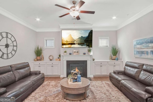 living room featuring a glass covered fireplace, light wood-type flooring, and ornamental molding