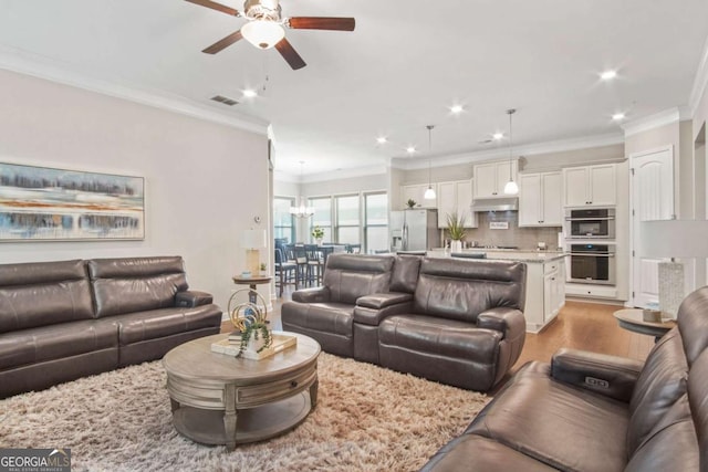 living area with a ceiling fan, recessed lighting, light wood-style floors, and ornamental molding