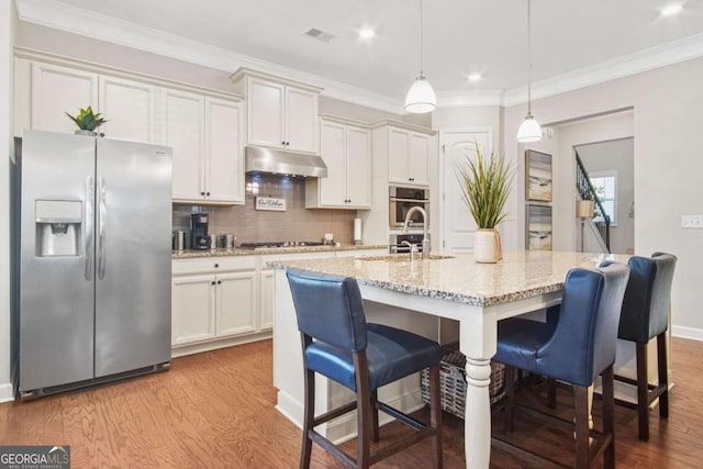 kitchen with wood finished floors, visible vents, under cabinet range hood, and stainless steel appliances