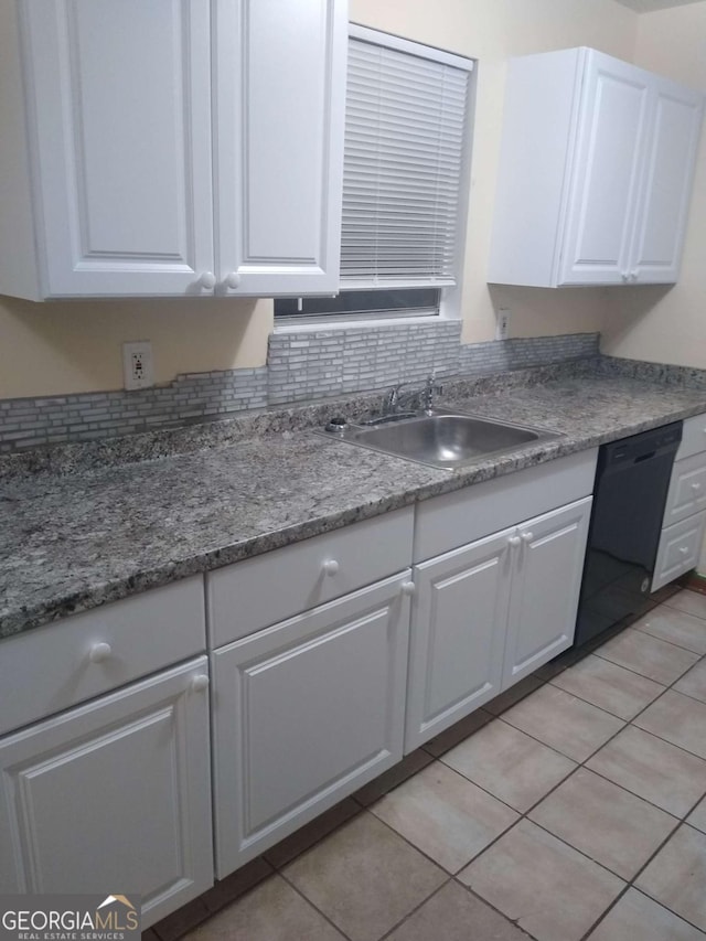 kitchen with black dishwasher, light tile patterned floors, decorative backsplash, white cabinetry, and a sink