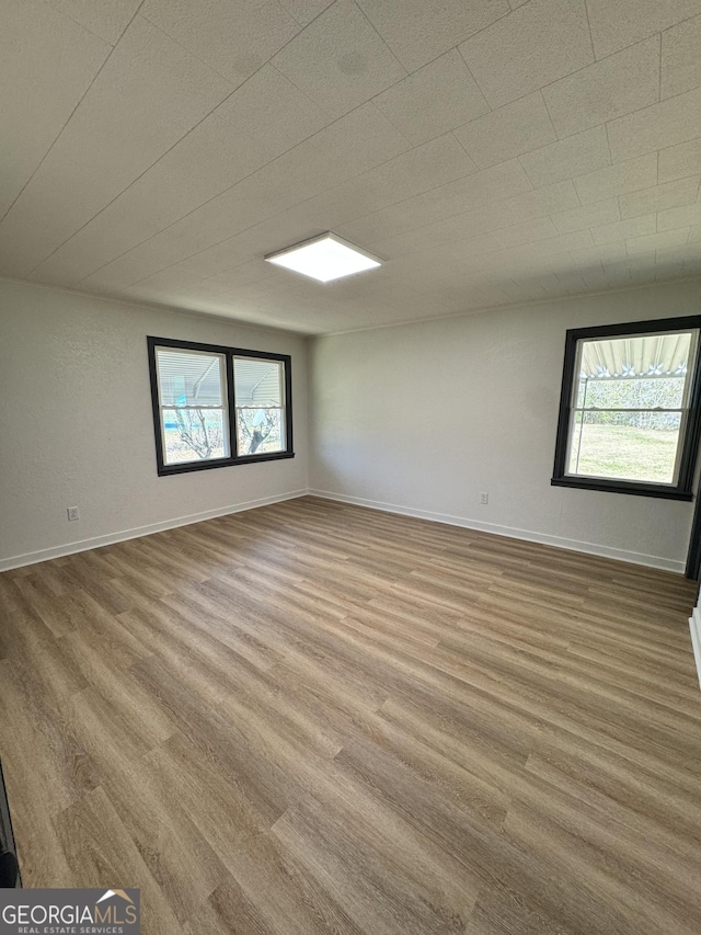 empty room with a healthy amount of sunlight, baseboards, and wood finished floors