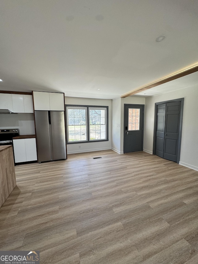 unfurnished living room featuring light wood-style floors, visible vents, and baseboards