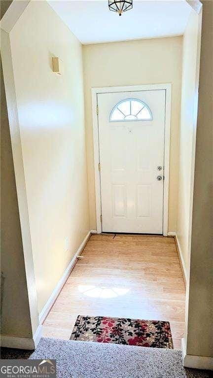 doorway featuring baseboards and light wood-type flooring