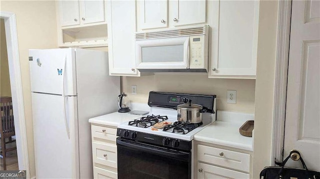 kitchen featuring white appliances, light countertops, and white cabinetry