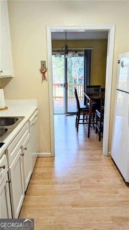 kitchen featuring light wood-style flooring, white appliances, white cabinetry, and light countertops