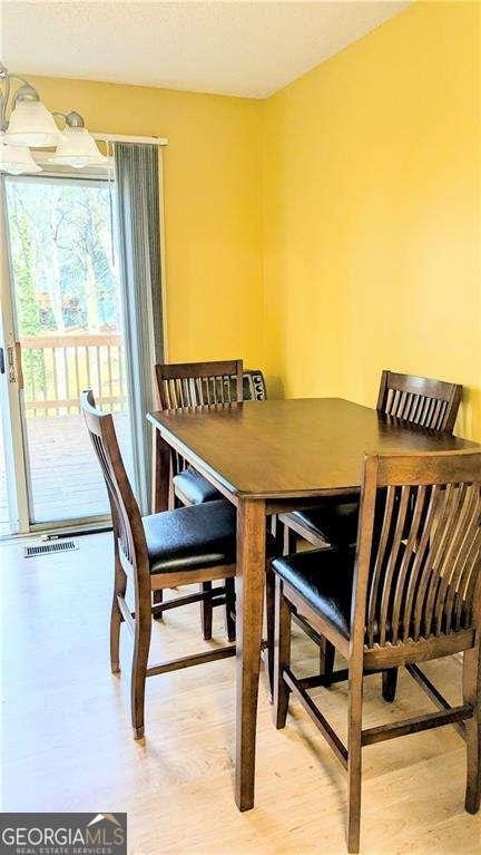 dining area featuring wood finished floors, visible vents, and a textured ceiling