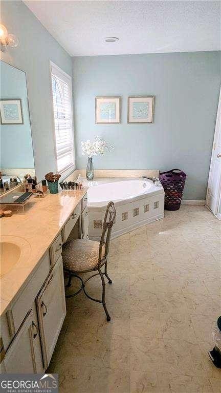 full bathroom featuring a textured ceiling, vanity, and a garden tub