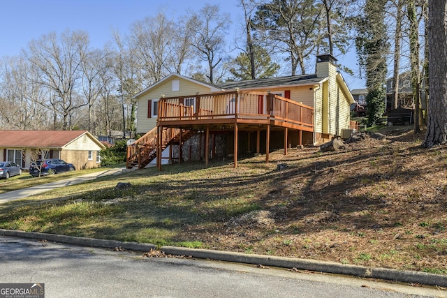 view of front of home featuring stairs, a chimney, and a wooden deck