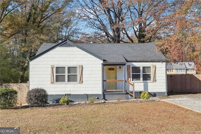 view of front of property with crawl space, roof with shingles, a front yard, and fence