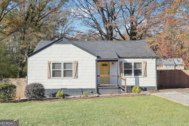 view of front of house featuring roof with shingles, a front lawn, and fence