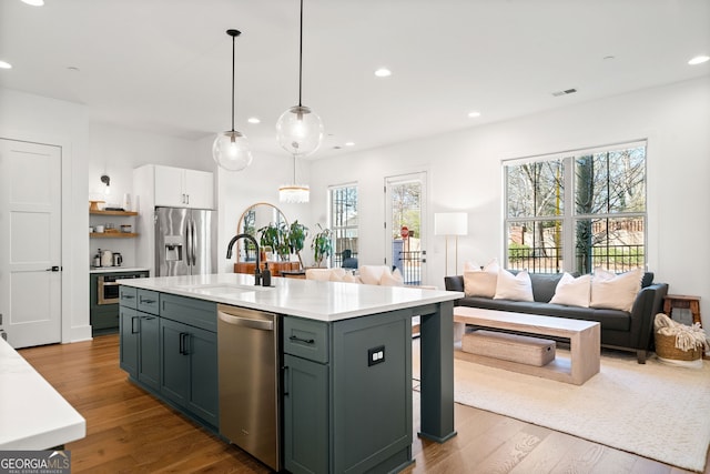 kitchen with a sink, light countertops, wood finished floors, and stainless steel appliances