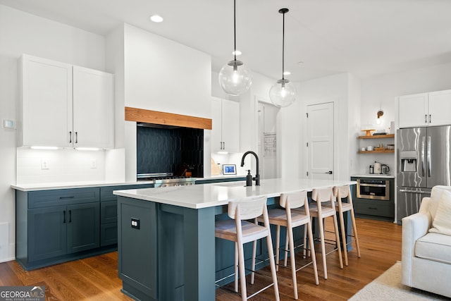 kitchen with tasteful backsplash, appliances with stainless steel finishes, wood finished floors, and light countertops