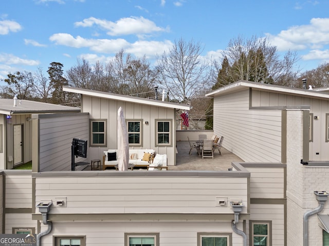 rear view of property with an outdoor living space and board and batten siding