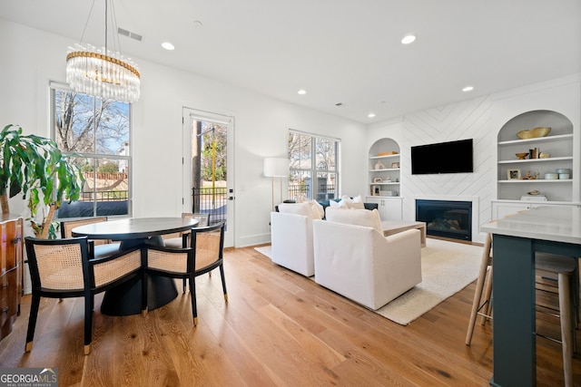 living area with built in shelves, a healthy amount of sunlight, visible vents, and a large fireplace