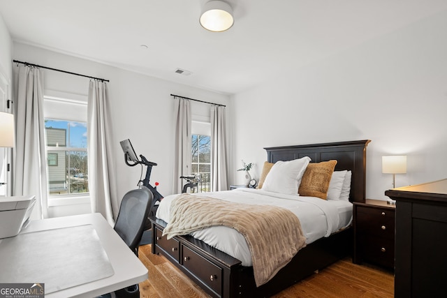 bedroom featuring multiple windows, wood finished floors, and visible vents