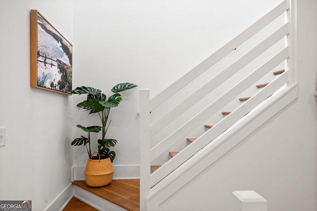 staircase featuring baseboards and wood finished floors