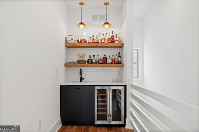 bar with beverage cooler, visible vents, dark wood-style flooring, a sink, and indoor wet bar